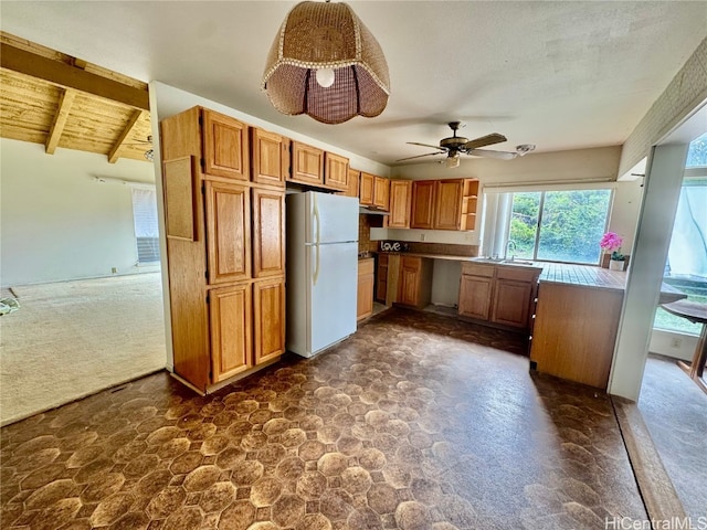 kitchen featuring sink, ceiling fan, vaulted ceiling with beams, white refrigerator, and wooden ceiling