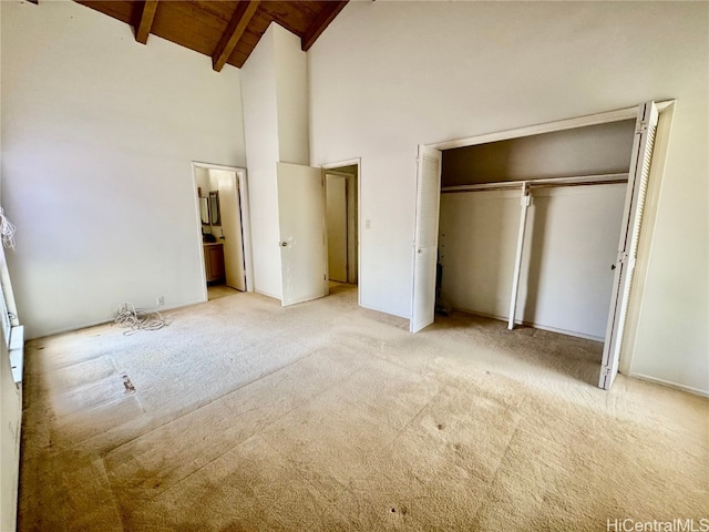 unfurnished bedroom featuring wood ceiling, beam ceiling, light colored carpet, and a closet