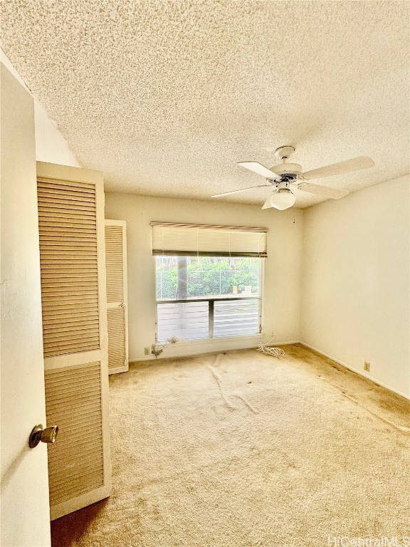 spare room featuring ceiling fan, a textured ceiling, and carpet