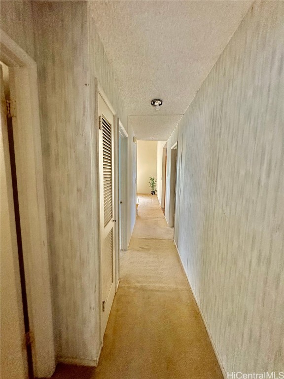 corridor featuring light carpet and a textured ceiling