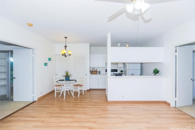 kitchen featuring white cabinetry, hanging light fixtures, kitchen peninsula, white fridge, and light hardwood / wood-style floors