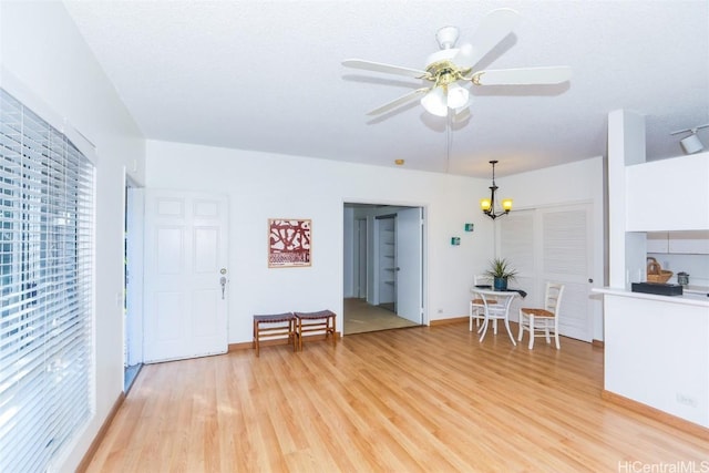 interior space with ceiling fan with notable chandelier and light hardwood / wood-style floors