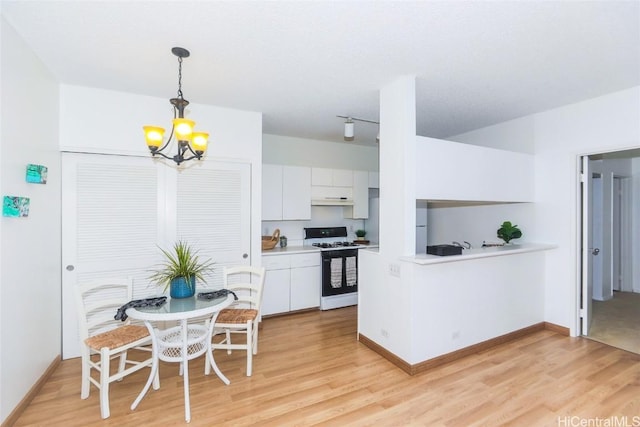 kitchen with white cabinetry, light hardwood / wood-style flooring, gas range gas stove, and pendant lighting