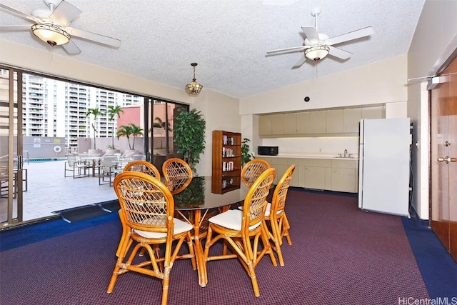 carpeted dining area with ceiling fan, vaulted ceiling, sink, and a textured ceiling