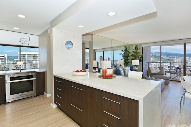 kitchen with dark brown cabinets, light hardwood / wood-style flooring, and oven