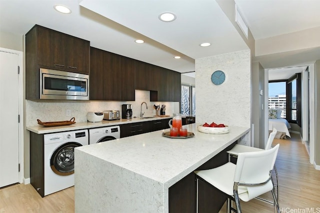 kitchen featuring stainless steel microwave, sink, decorative backsplash, and a breakfast bar area