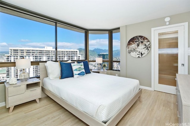 bedroom with expansive windows and light hardwood / wood-style floors