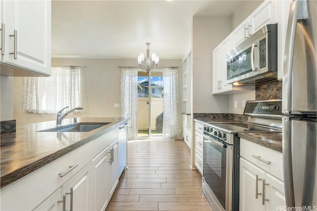 kitchen with pendant lighting, sink, white cabinets, a notable chandelier, and stainless steel appliances