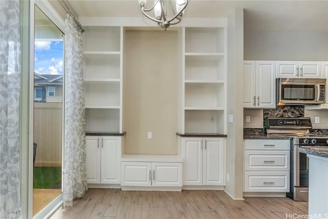 kitchen with white cabinetry, backsplash, stainless steel appliances, a notable chandelier, and light wood-type flooring