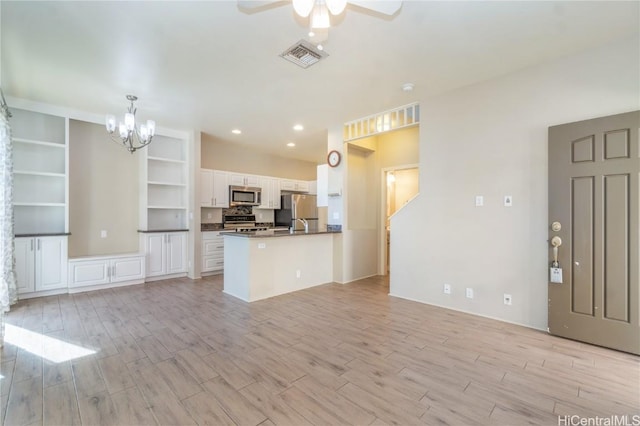 kitchen featuring white cabinetry, stainless steel appliances, ceiling fan with notable chandelier, kitchen peninsula, and light wood-type flooring