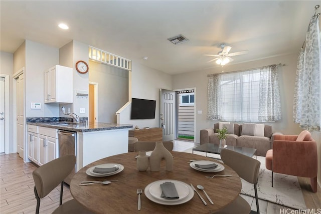 dining area with sink, ceiling fan, and light wood-type flooring