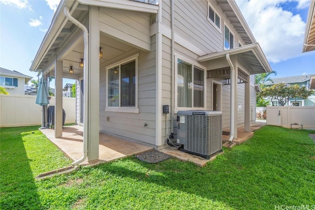 rear view of property with central AC unit, a lawn, and a patio