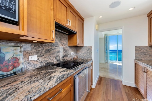 kitchen featuring stone countertops, decorative backsplash, black electric stovetop, wall oven, and light hardwood / wood-style floors