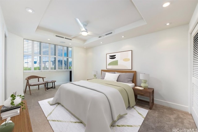 bedroom featuring ceiling fan, a raised ceiling, and light carpet