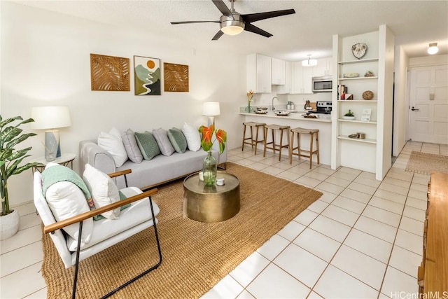 living room featuring light tile patterned flooring, sink, and ceiling fan