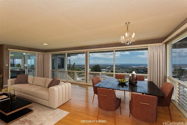 interior space with plenty of natural light, a textured ceiling, a notable chandelier, and light wood-type flooring