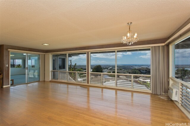 unfurnished room featuring plenty of natural light, a chandelier, and light hardwood / wood-style flooring