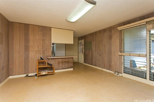 unfurnished living room featuring a textured ceiling and wood walls