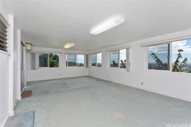 unfurnished room with a wall unit AC, carpet, and a textured ceiling