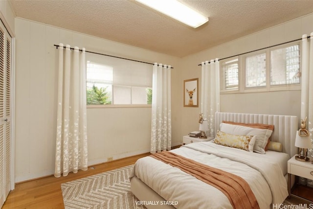 bedroom with hardwood / wood-style floors, a closet, and a textured ceiling