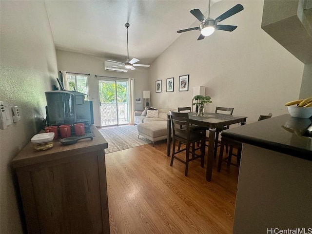 dining area featuring high vaulted ceiling, a wall mounted air conditioner, ceiling fan, and light hardwood / wood-style flooring