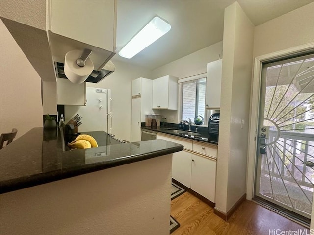 kitchen featuring white refrigerator, kitchen peninsula, sink, and white cabinets