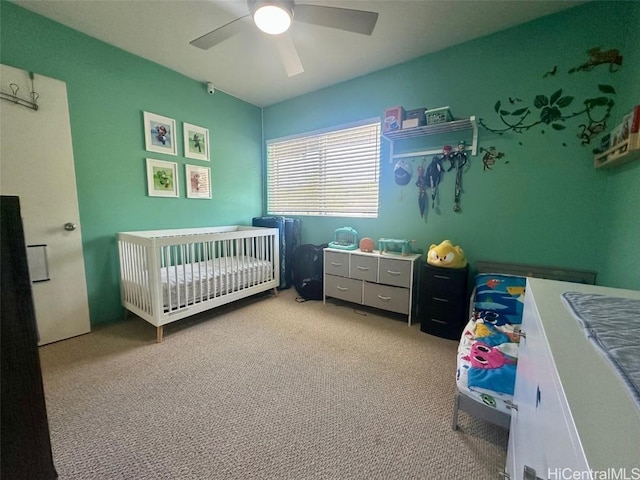 bedroom with a nursery area, light carpet, and ceiling fan