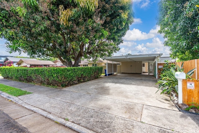 view of front of property featuring a carport, driveway, and fence