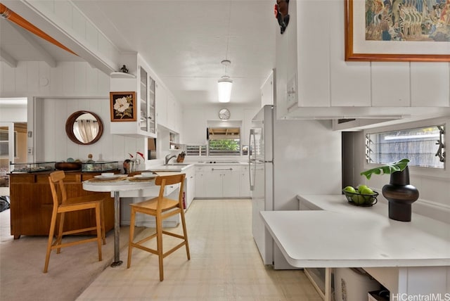 kitchen featuring a healthy amount of sunlight, light floors, white cabinetry, and a sink