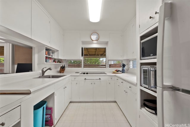 kitchen featuring black electric cooktop, light countertops, freestanding refrigerator, light floors, and stainless steel microwave