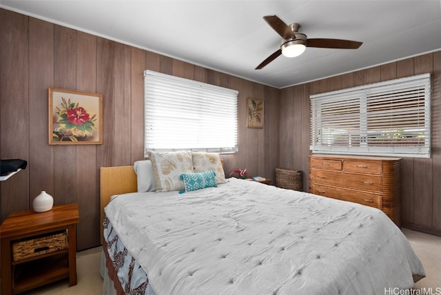 bedroom with light carpet, ceiling fan, and wooden walls