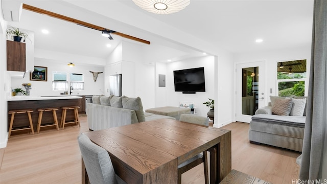 dining space with vaulted ceiling with beams, sink, and light wood-type flooring