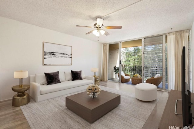 living room featuring ceiling fan, expansive windows, a textured ceiling, and wood finished floors