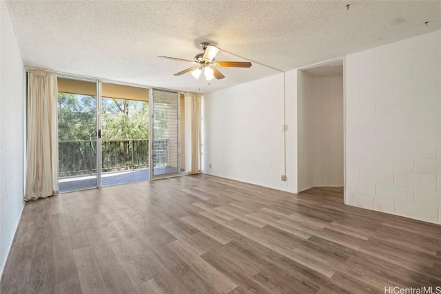 unfurnished room featuring wood finished floors, floor to ceiling windows, a ceiling fan, and a textured ceiling