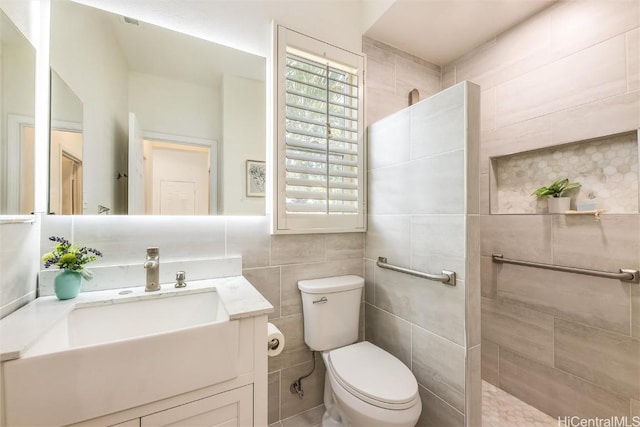 bathroom featuring tile walls, vanity, toilet, and a tile shower