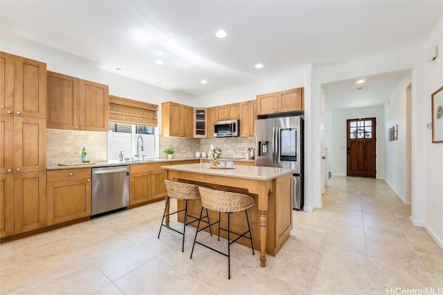 kitchen featuring sink, a breakfast bar, appliances with stainless steel finishes, a center island, and tasteful backsplash