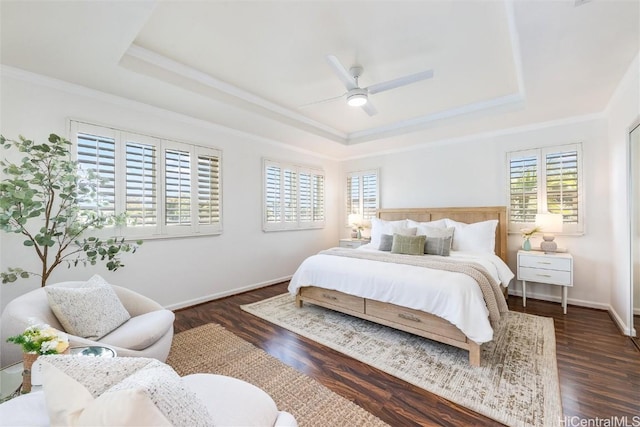 bedroom with dark wood-type flooring, a tray ceiling, and multiple windows