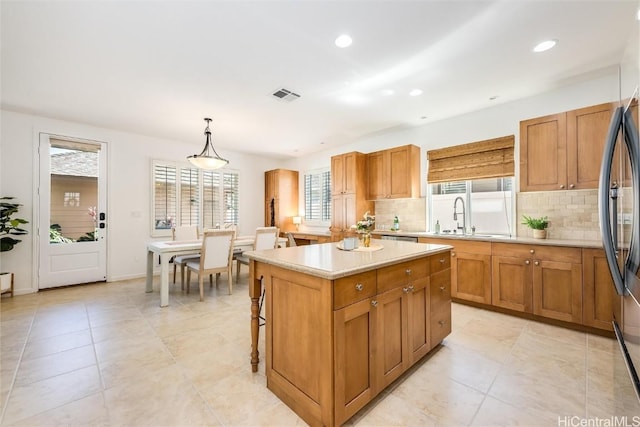 kitchen with hanging light fixtures, a center island, sink, and backsplash