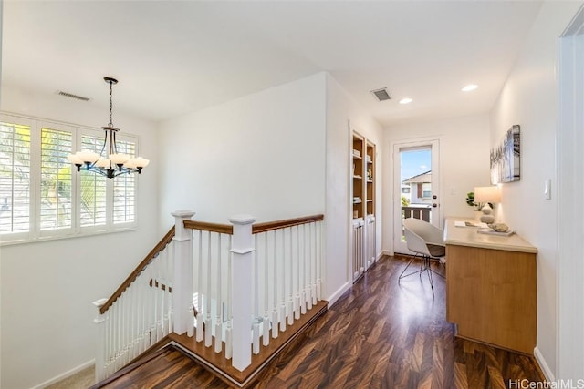 hall featuring dark hardwood / wood-style flooring, a wealth of natural light, and a chandelier