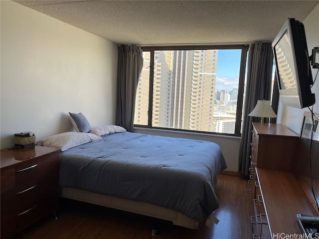 bedroom with a textured ceiling and dark hardwood / wood-style flooring