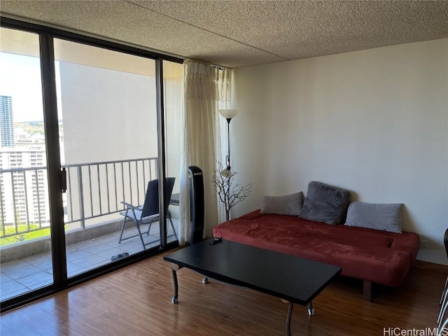 sitting room with wood-type flooring, floor to ceiling windows, and a textured ceiling