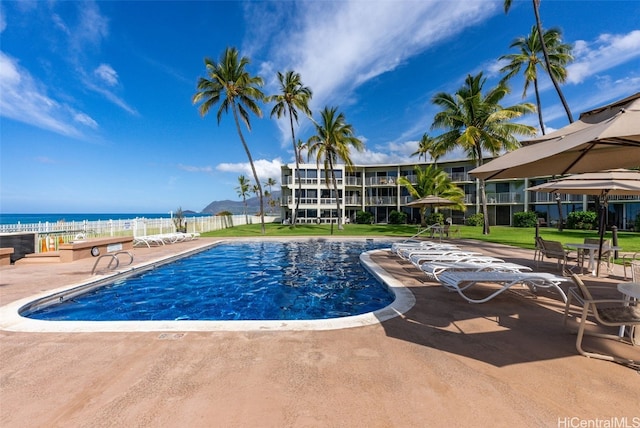 view of pool with a lawn, a patio, and a water view