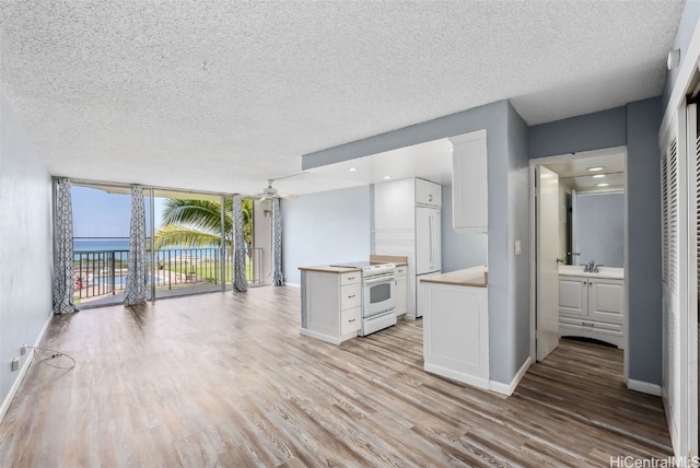 87-561 Farrington Hwy Unit 211, Waianae, HI 96792 - kitchen with white electric stove, white cabinets, a textured ceiling, a ceiling fan, and light wood-type flooring