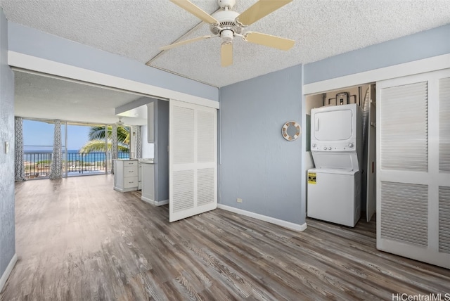 interior space with ceiling fan, stacked washer / drying machine, wood-type flooring, and a textured ceiling