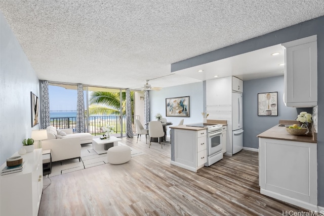 kitchen featuring white cabinetry, a water view, white appliances, and light hardwood / wood-style floors