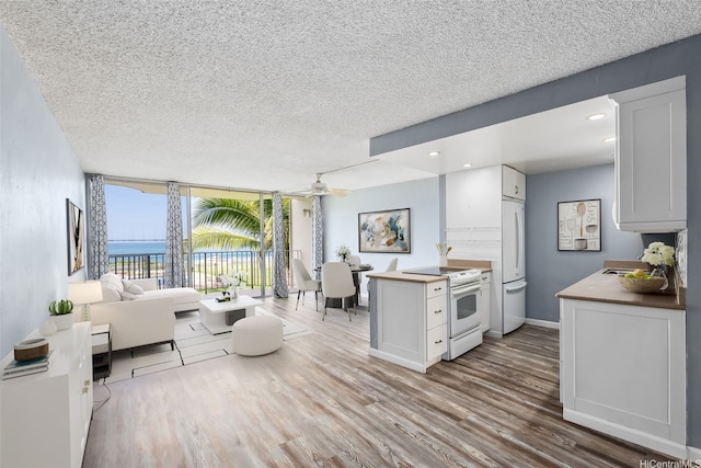 87-561 Farrington Hwy Unit 211, Waianae, HI 96792 - living room with ceiling fan, wood finished floors, a textured ceiling, a water view, and a wall of windows