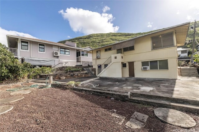 back of property featuring a mountain view and a wall unit AC