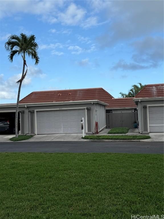 view of front of house with a tiled roof, a front yard, and driveway