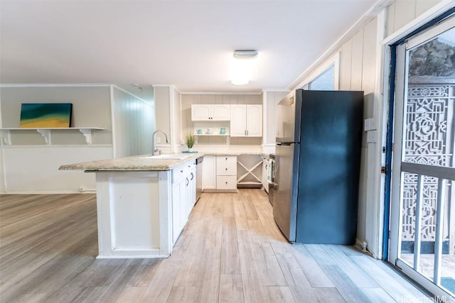 kitchen with a sink, light wood-style flooring, appliances with stainless steel finishes, and white cabinets