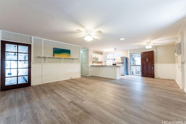 unfurnished living room with light wood-style flooring, a healthy amount of sunlight, and ceiling fan